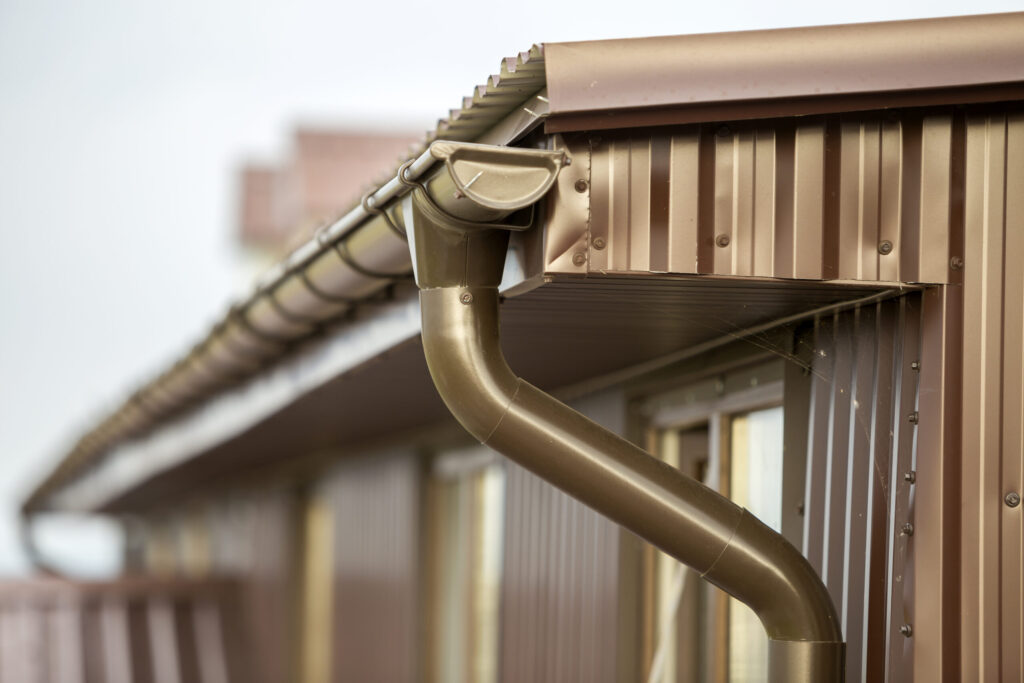 close-up-detail-cottage-house-corner-with-metal-planks-siding-roof-with-gutter-rain-system-scaled.jpg