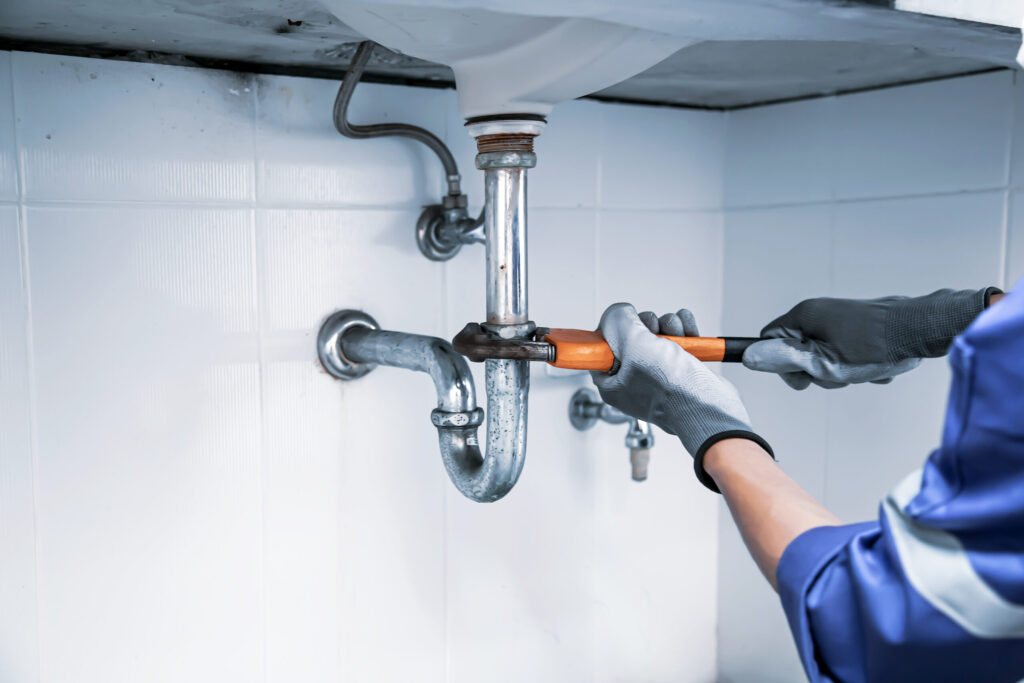 plumber-using-wrench-repair-water-pipe-sink-scaled.jpg